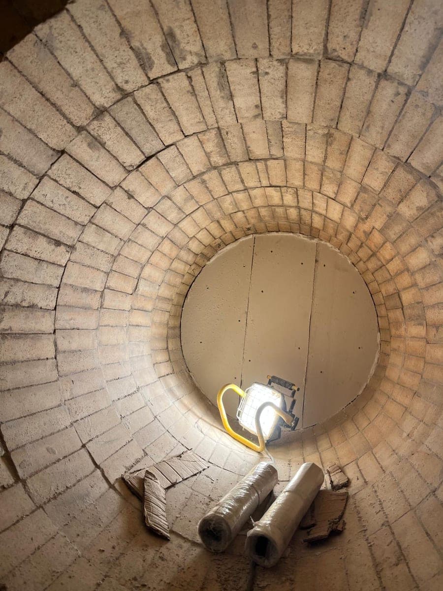 Rundes Mauerwerk im Schacht von unten mit Arbeitsleuchte