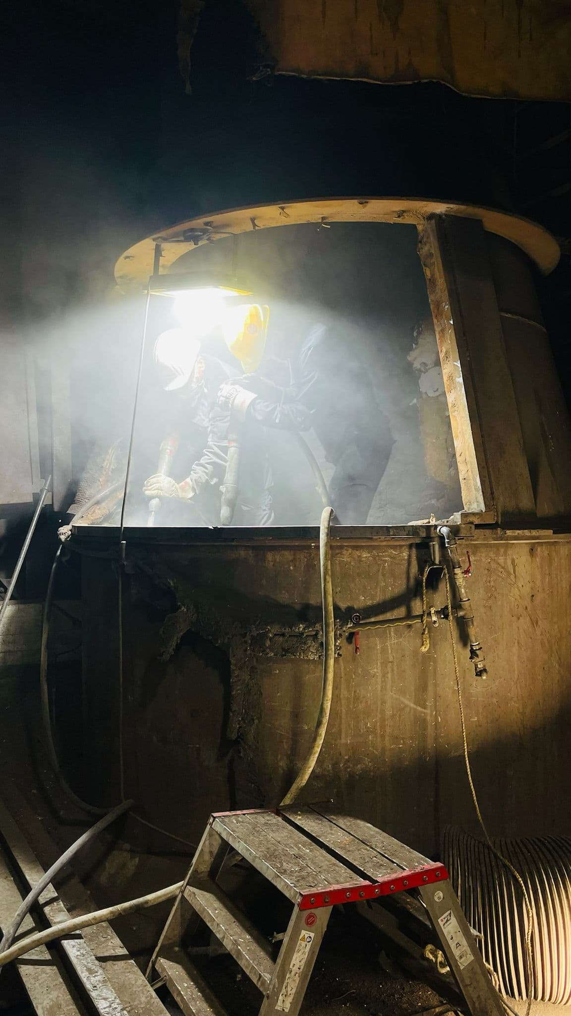 Workers carrying out demolition work in an industrial furnace